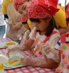 フルーツを盛り付け、チョコスプレーをかけ、クレープの形を整えたらできあがり！ 学生は子どもの横でそっと見守ります。